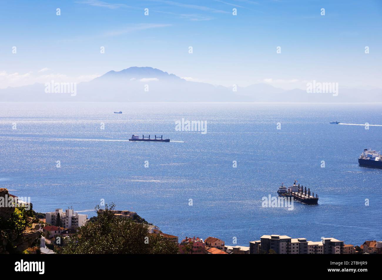 Ships transit through the Straight of Gibraltar with Jebel Musa in Morocco, Africa in view. The British Overseas Territory of Gibraltar, the Rock of G Stock Photo