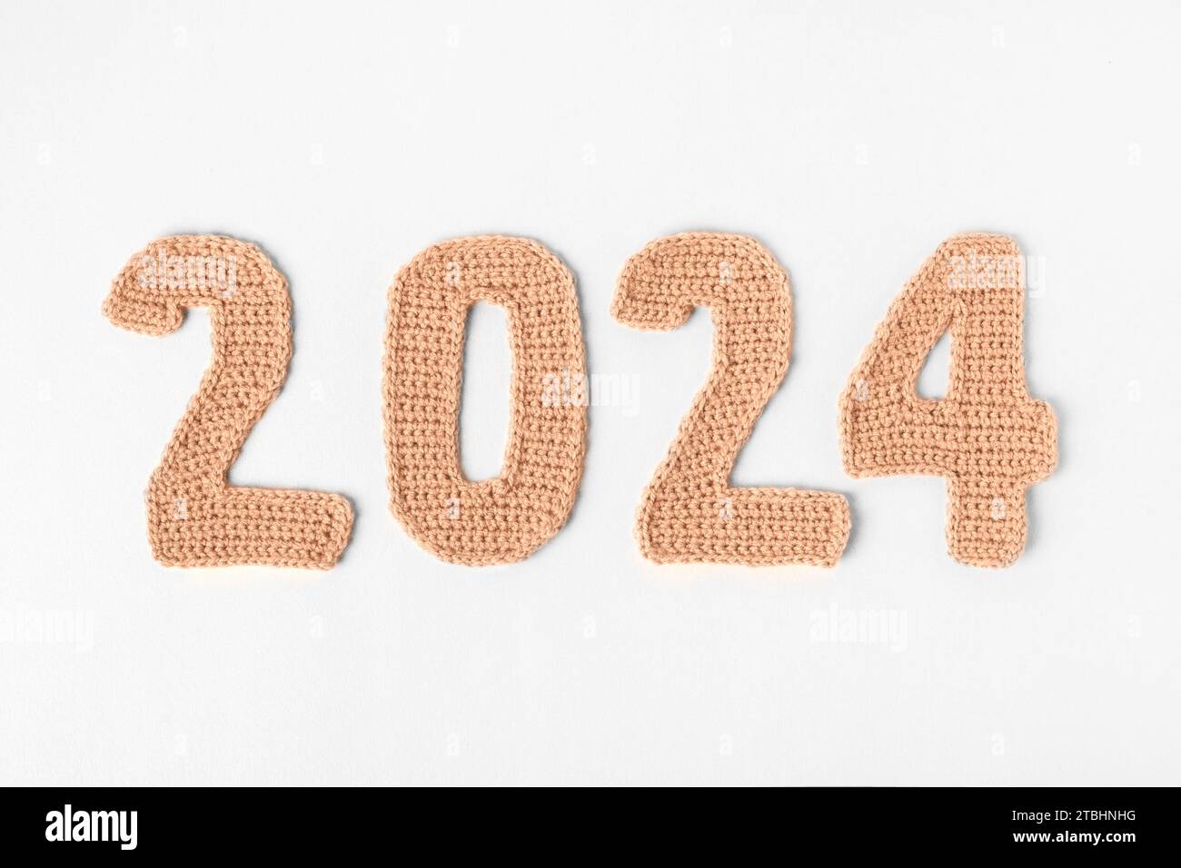 Demonstrating the colors of 2024 - Peach Fuzz. Knitted numbers 2024 peach colors. Stock Photo