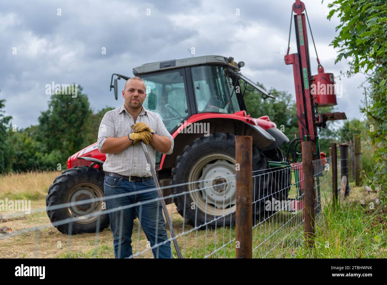 Fencing contractor with tools of his trade erecting a wire netting livestock fence. Co. Durham