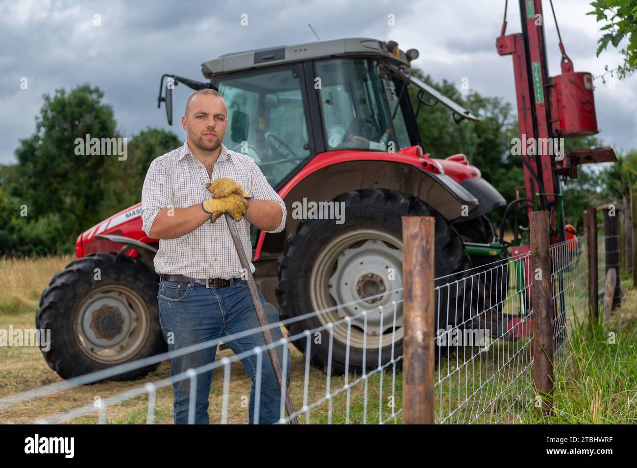 Fencing contractor with tools of his trade erecting a wire netting livestock fence. Co. Durham