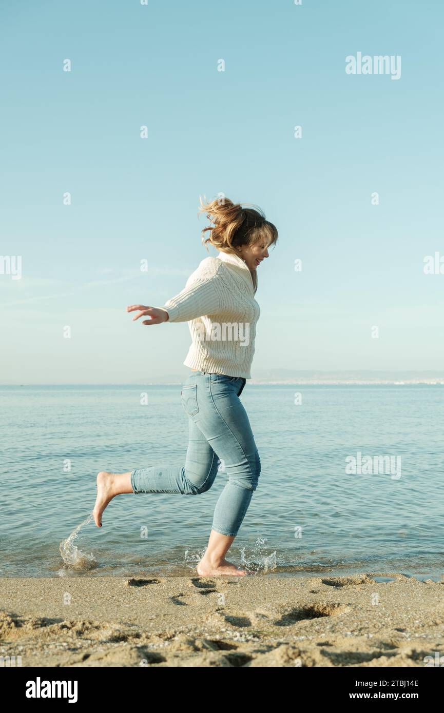 Happy young woman running by the sea Stock Photo - Alamy