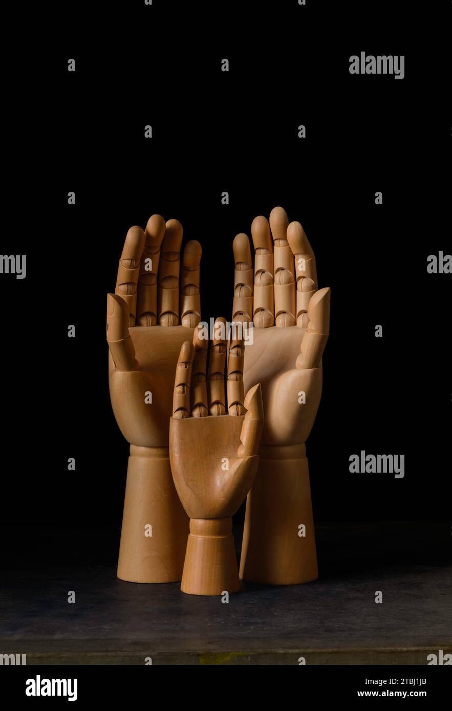 Three wooden mannequin hands against a black background Stock Photo