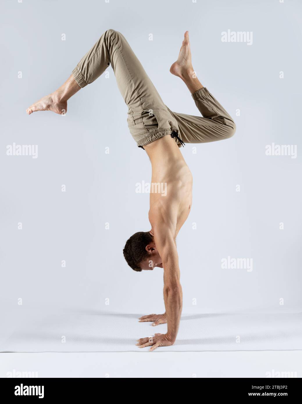 athletic man practicing yoga on a white mat with a white background Stock Photo