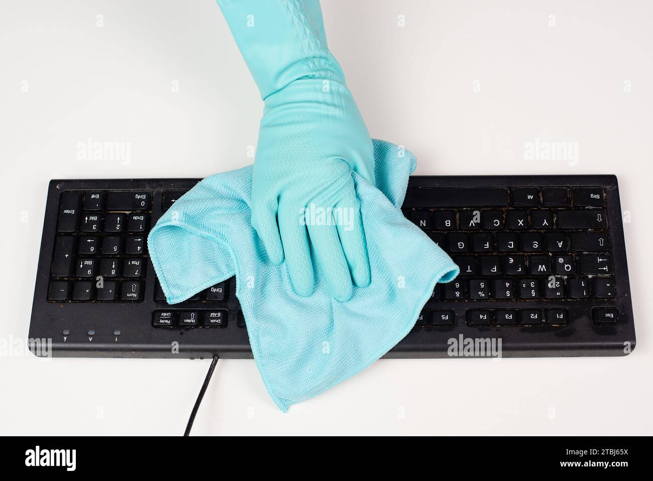 Cleaning computer keyboard in office with a wet wipe rag, dusty and ...