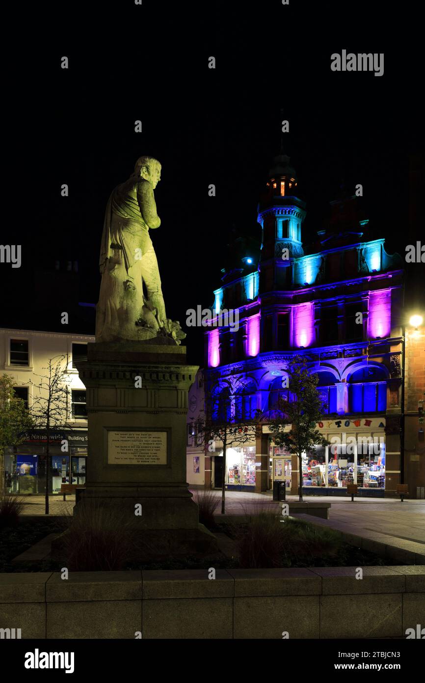 The poet Robert Burns statue in Dumfries town centre, Greyfriars Church behind at night Scotland UK Stock Photo