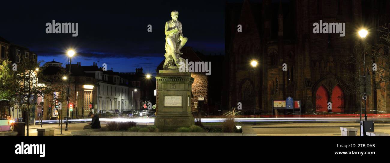 The poet Robert Burns statue in Dumfries town centre, Greyfriars Church behind at night Scotland UK Stock Photo