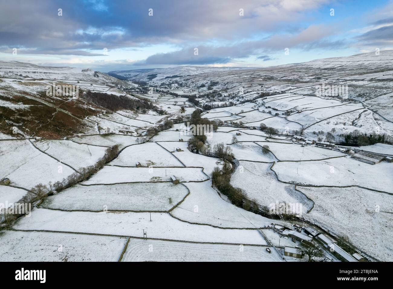 Looking down a snow covered Swaledale in early winter, with the hamlet of Thwaite in the foreground and the River Swale meandering down the dale. York Stock Photo