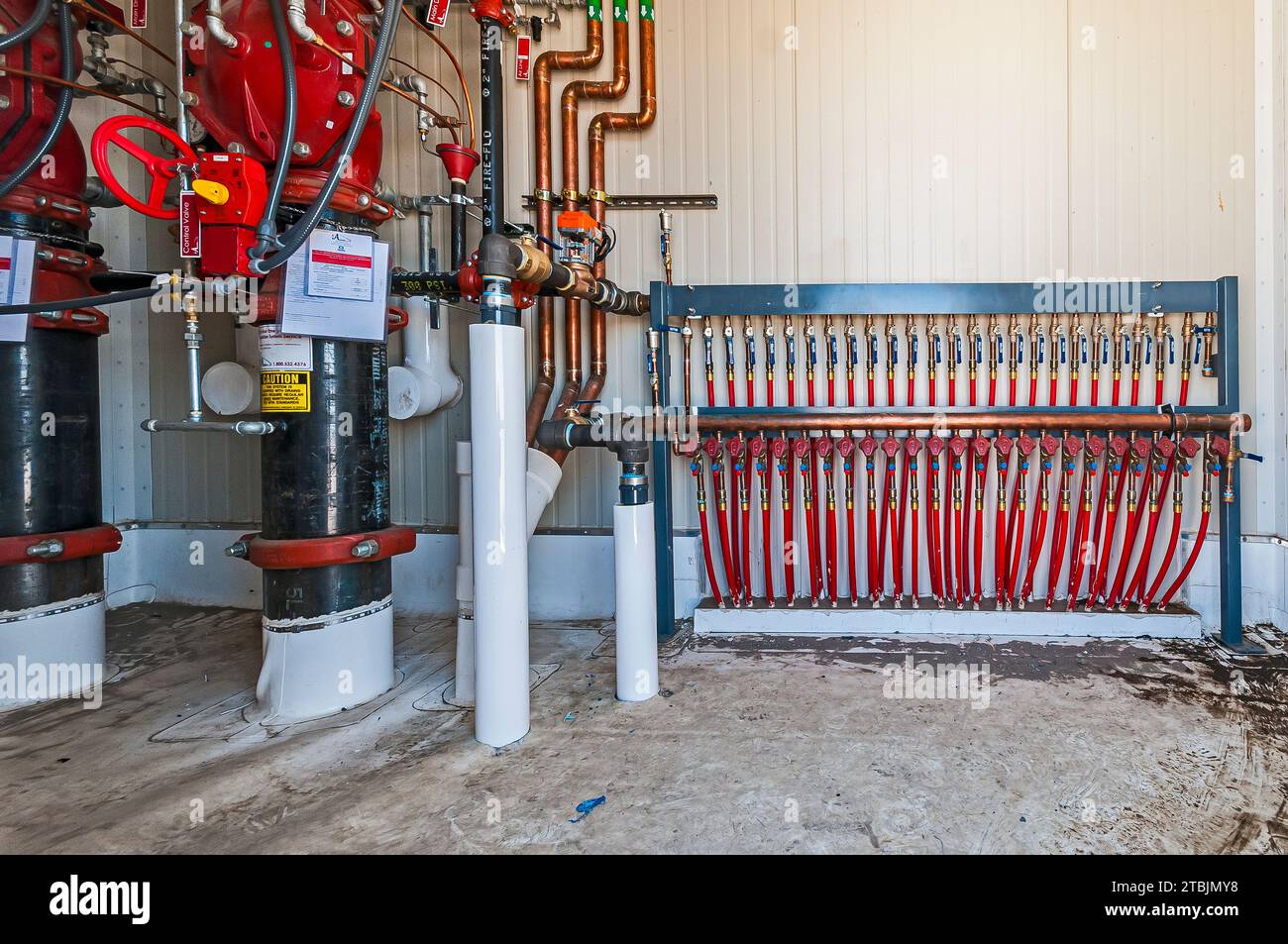 A rack of valves and red hoses in a small control room on the roof of a ...
