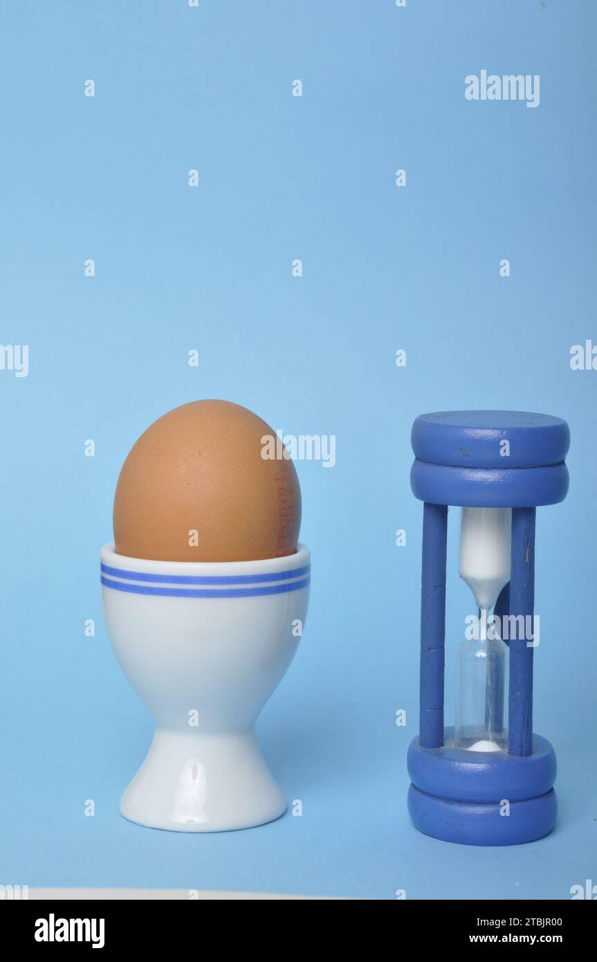 Boiled egg and hourglass on a blue background Stock Photo