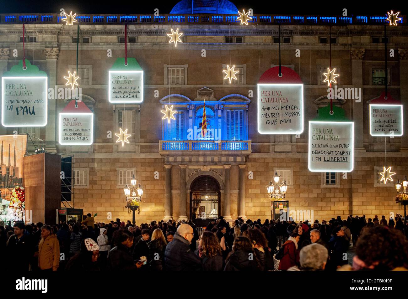 People visit downtown Barcelona where the main facade of the Catalan government headquarters (Generalitat de Catalunya) appears decorated with lights and Christmas motifs. Stock Photo