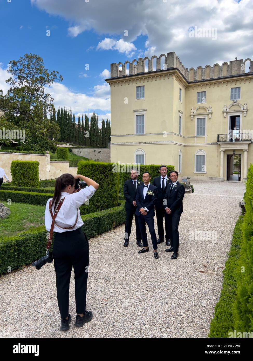 Rome, Italy - 09 august 2023: Photographer girl shoots the groom with his friends in the garden of an old mansion Stock Photo