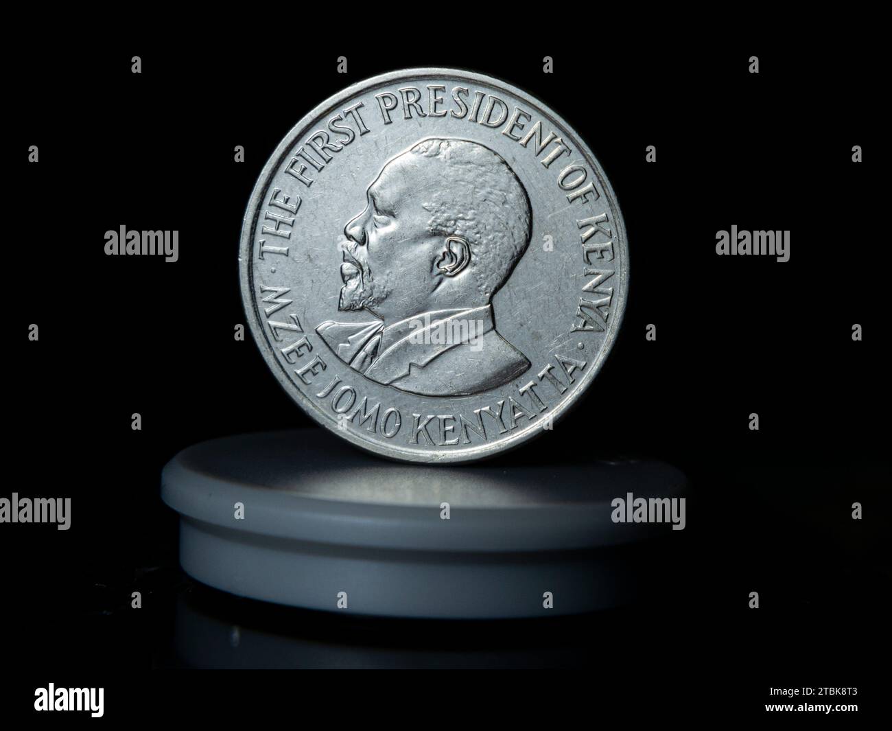 An isolated, silver-colored coin featuring a portrait of a President on the front is shown in the foreground with a plain background Stock Photo