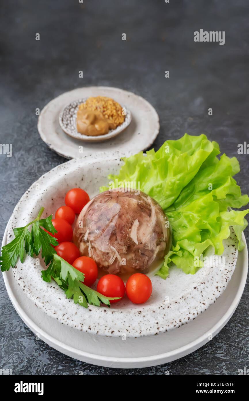 Homemade jellied meat with mustard and horseradish on the table. Aspic. Homemade jelly with mustard, tomatoes and garlic on the table. Kholodets, trad Stock Photo