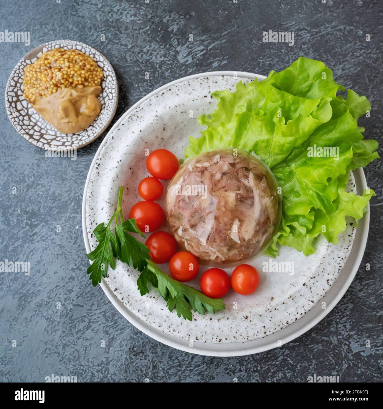 Homemade jellied meat with mustard and horseradish on the table. Aspic. Homemade jelly with mustard, tomatoes and garlic on the table. Kholodets, trad Stock Photo