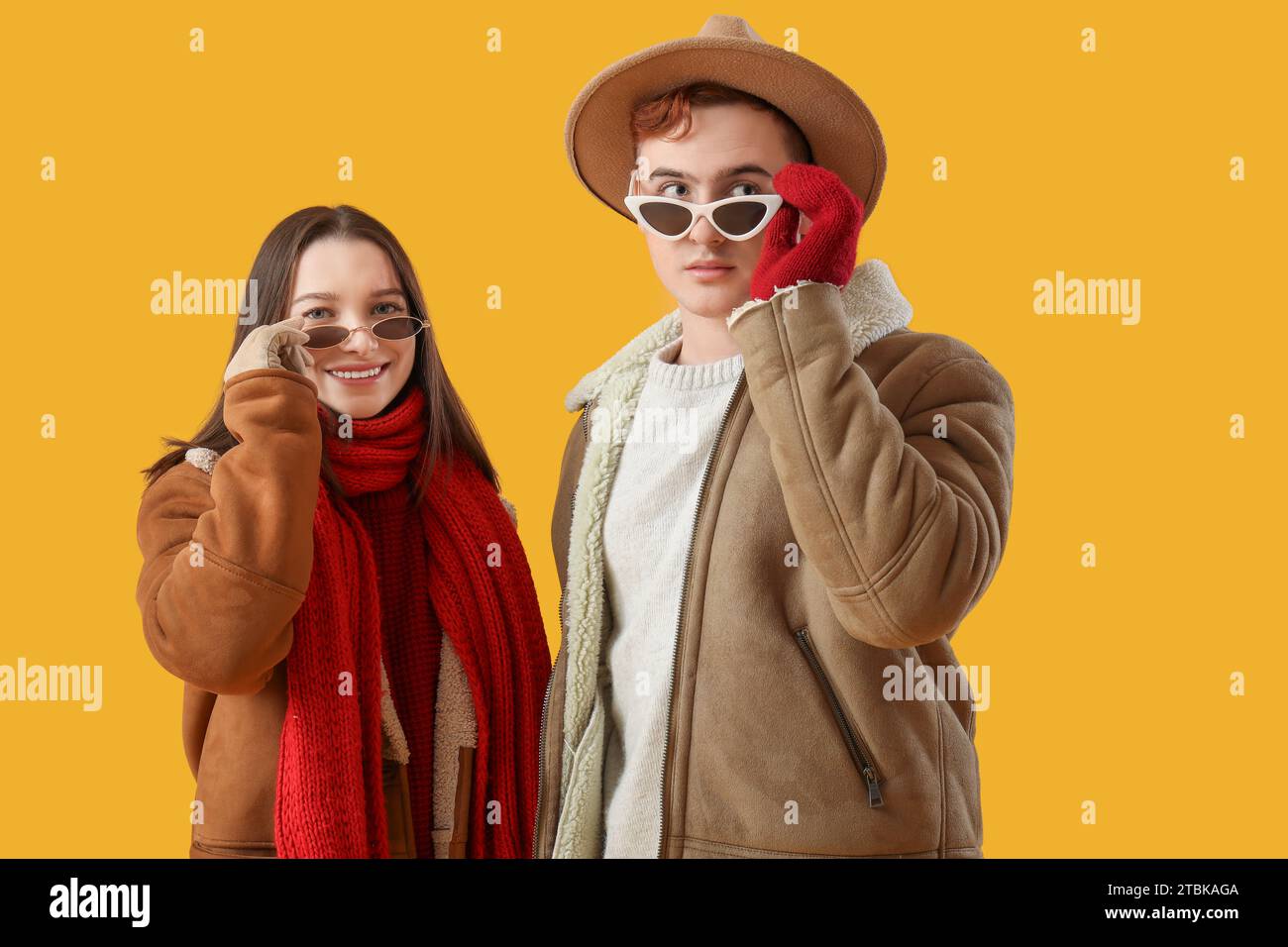 Young couple in winter clothes on yellow background Stock Photo