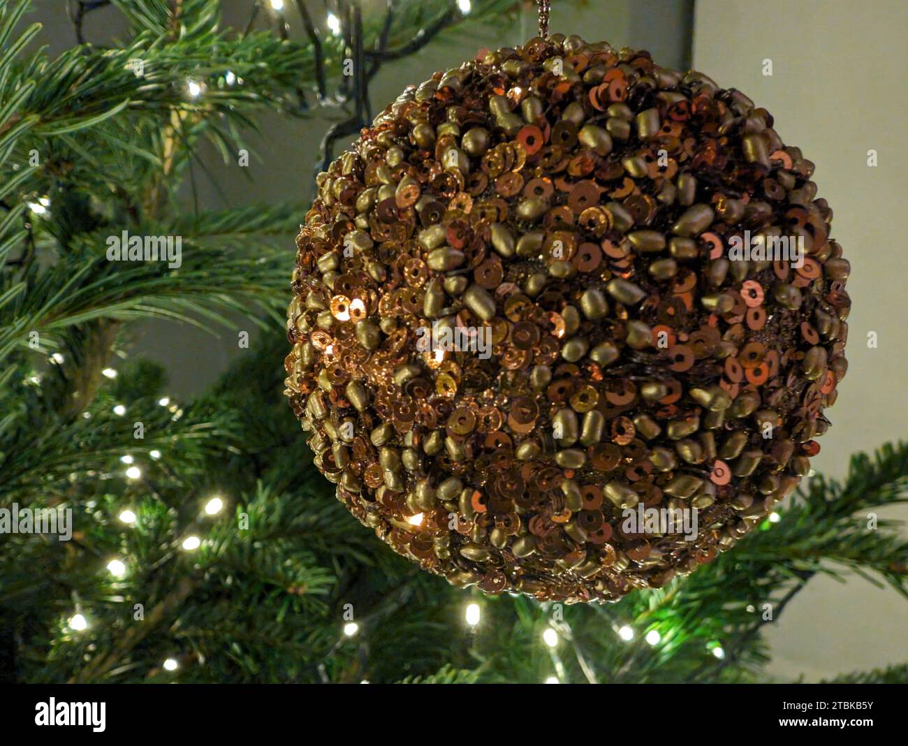 A festive decoration featuring a colorful beaded ball ornament suspended from an evergreen Christmas tree Stock Photo