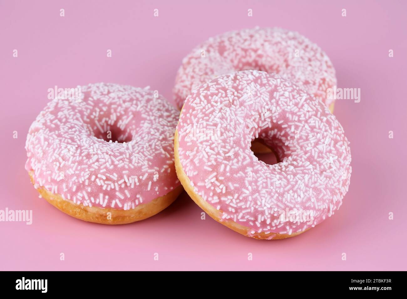 Three fresh donuts on pink background. Stock Photo