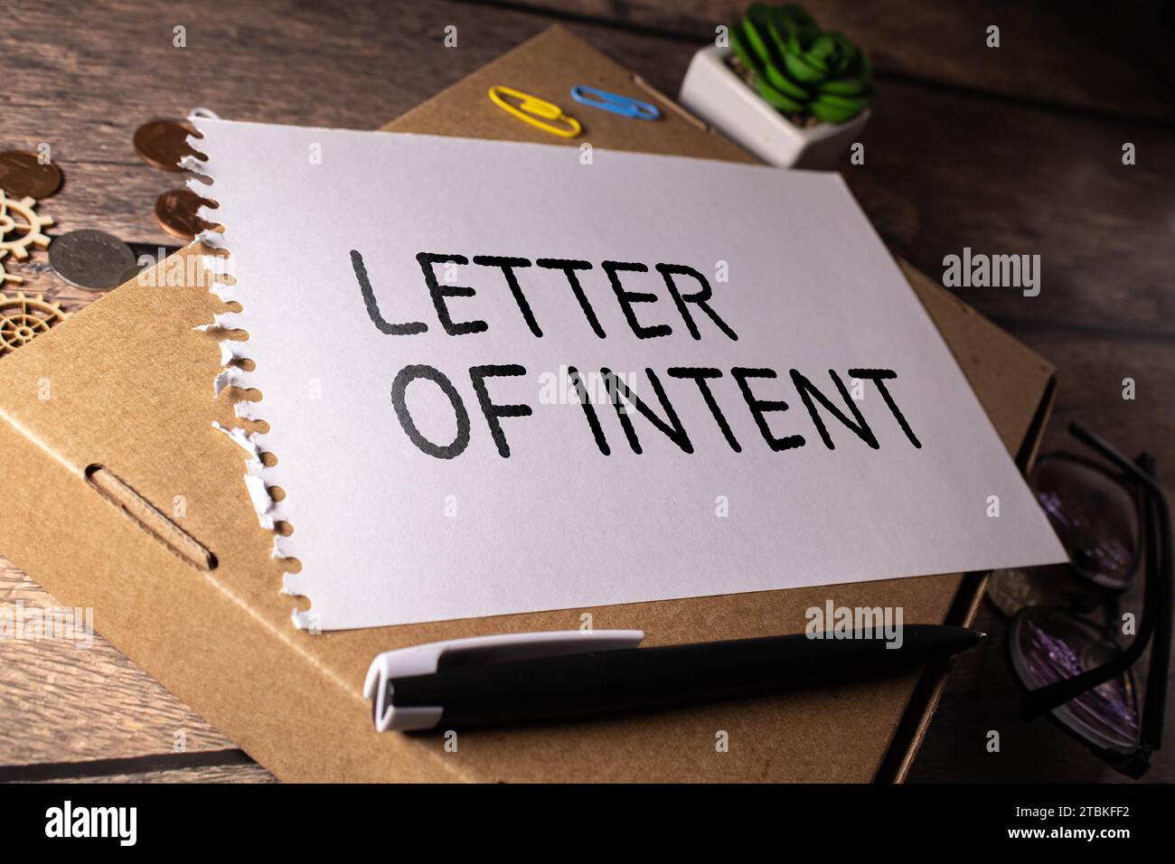LETTER OF INTENT text on a paper clipboard with magnifier and keyboard on wooden background. Stock Photo