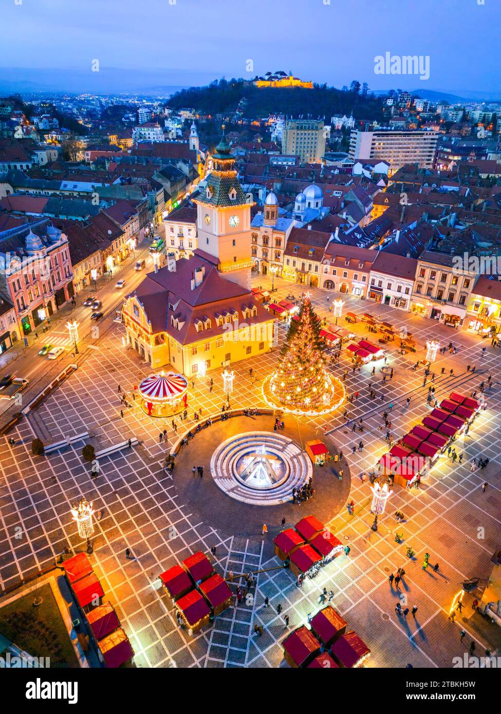 Brasov, Romania. Aerial drone view with Christmas Market in Main Square twilight beautiful lights, Transylvania holiday destination. Stock Photo