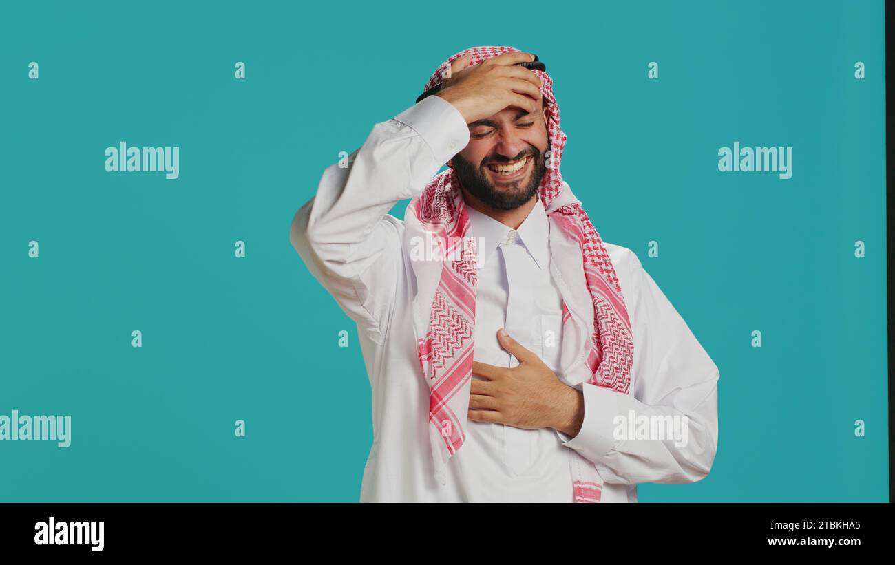 https://c8.alamy.com/comp/2TBKHA5/cheerful-person-laughing-at-a-joke-in-studio-having-fun-while-he-wears-muslim-traditional-clothing-and-kufiyah-young-arab-man-enjoying-laugh-with-people-expressing-happiness-and-joy-2TBKHA5.jpg
