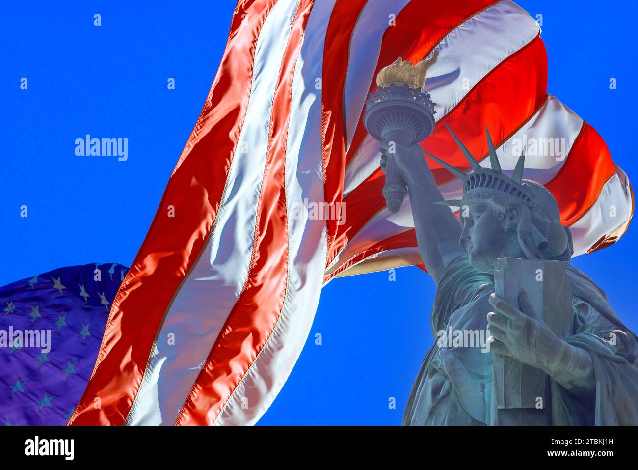 Statue of Liberty is paired with an American flag with beautifully waving stars and stripes as background Stock Photo