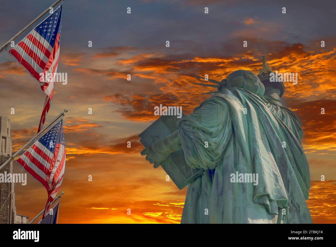 Statue of Liberty is framed by beautifully waving American flag during sunset Stock Photo