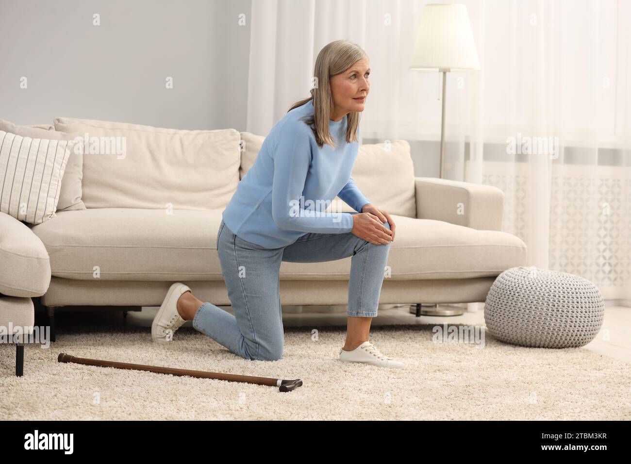 Mature woman with walking cane suffering from knee pain at home