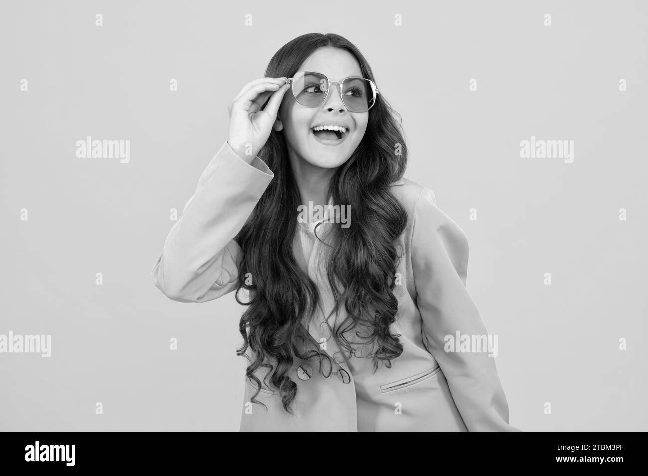 Cute school girl wearing sunglasses on yellow studio background, girl in glasses. Stock Photo