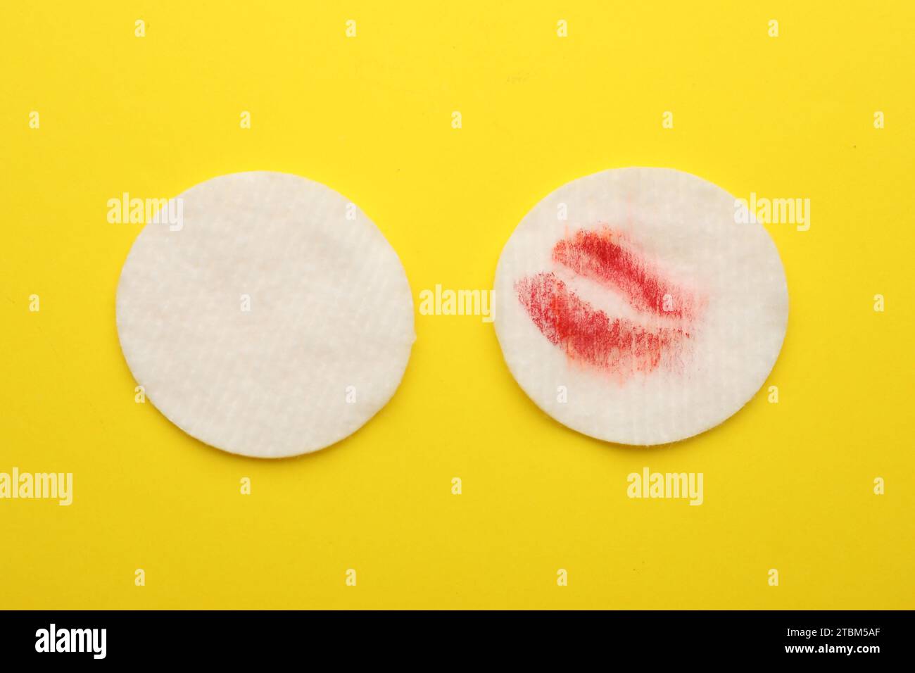 Clean and dirty cotton pads after removing makeup on yellow background