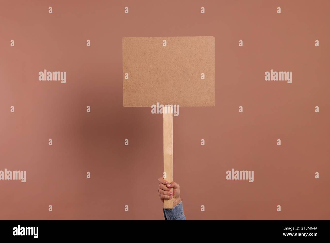 Man holding blank sign on brown background, closeup. Space for text Stock Photo