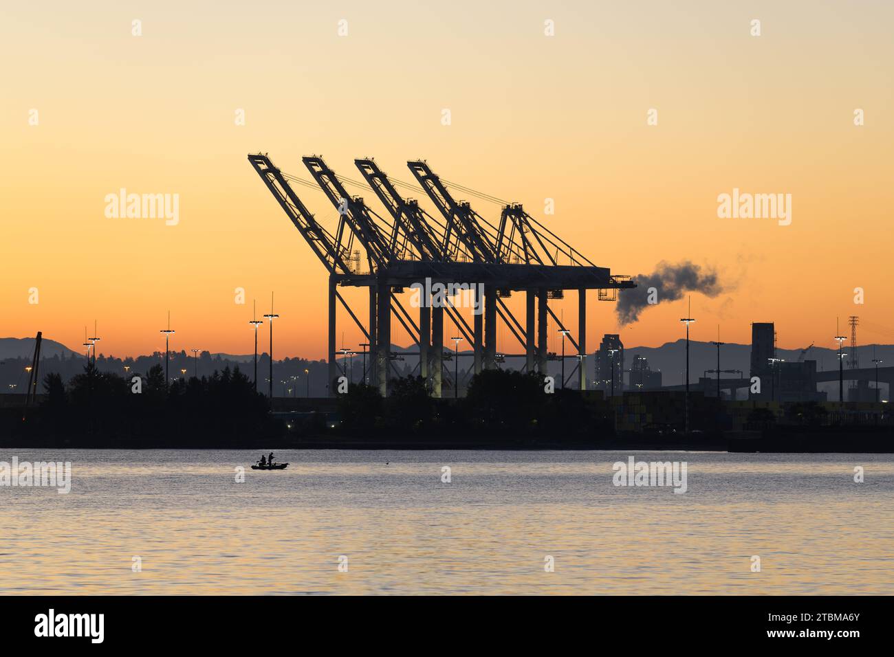 Seattle, WA, USA - October 29, 2023; Row of raised SSA Terminal industrial cranes at dawn in Seattle with orange sky Stock Photo