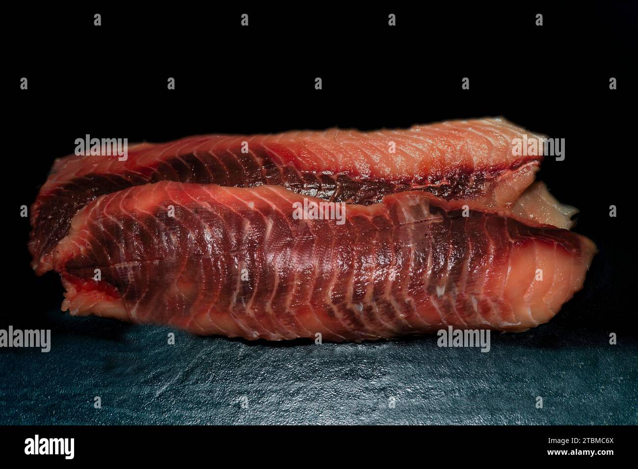 Trimmed fillets of grass carp (Ctenopharyngodon idella), also known as white Amur, wild catch from Myramar, food photography with black background Stock Photo