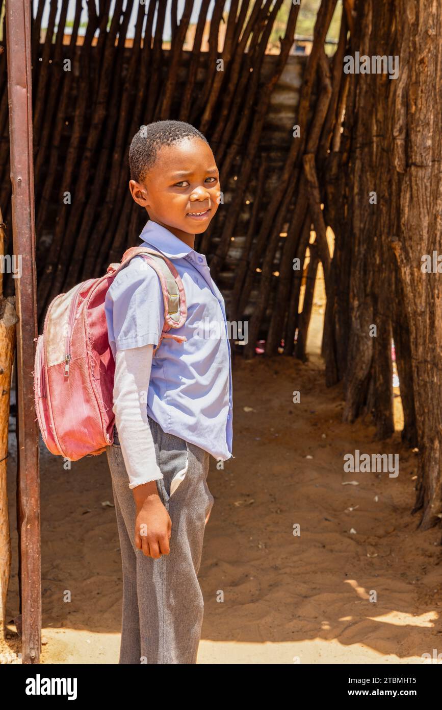village poor african boy with a backpack wearing an uniform going to school Stock Photo