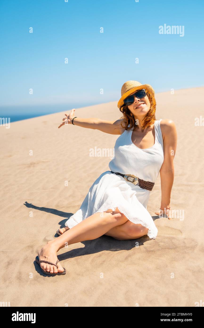 Vertical photo of a woman showing an idyllic coastal landscape sitting on the sand in Cabo de Gata, Spain Stock Photo