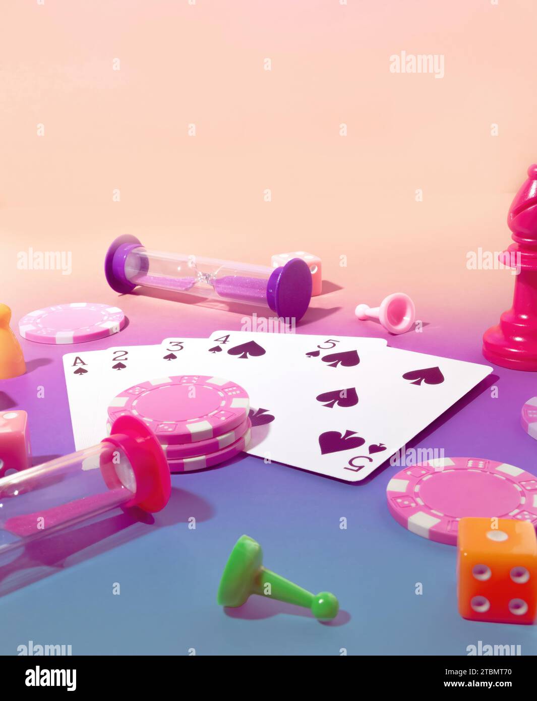 Game Scene with Poker Chips, Playing Cards, Chess Pieces, Dice, Gaming Sand Timers and Board game Pawns on a Pastel Pink & Blue Background on Stock Photo