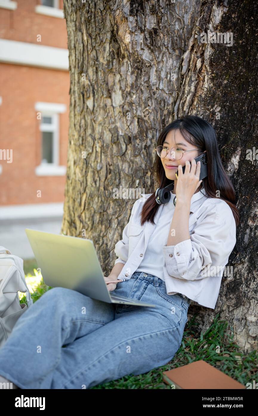 A happy and positive young Asian female college student is talking on ...