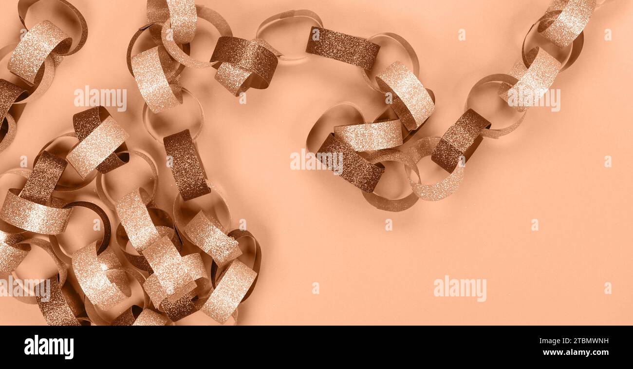 Strips of gold silver red sparkling chain garland. Image toned in Peach Fuzz color of the year 2024. Festive Christmas birthday decoration garland. Sp Stock Photo