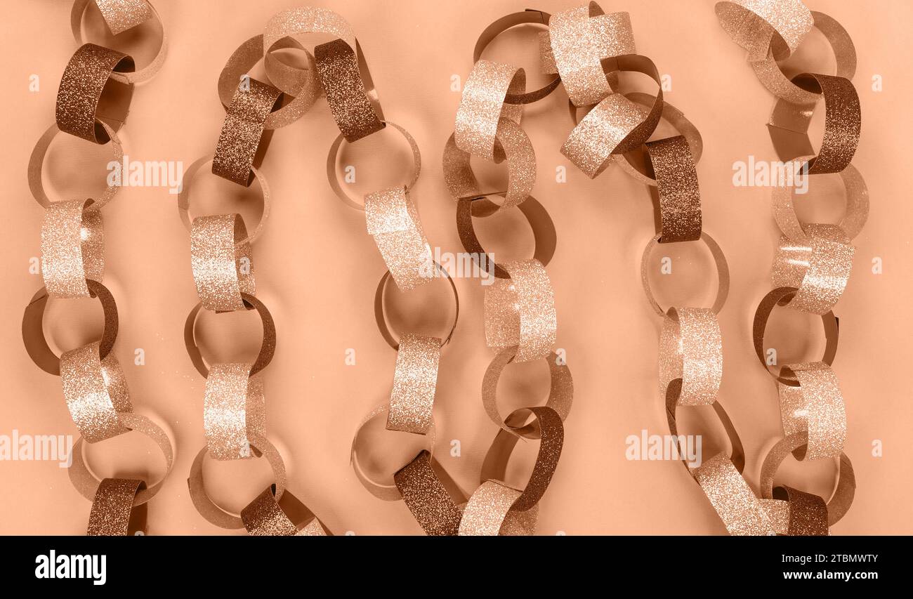 Background with strips of gold silver red sparkling chain garland. Image toned in Peach Fuzz color of the year 2024. Festive Christmas birthday decora Stock Photo