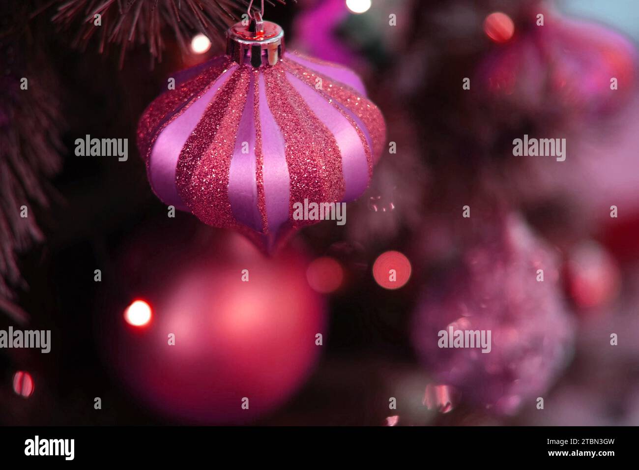 Christmas Ornaments Background. Gold and Pink Ornamented Glass Bauble. Christmas Tree with Globes, Bubbles. Shiny Sparkle Balls, Xmas Branches. Decora Stock Photo