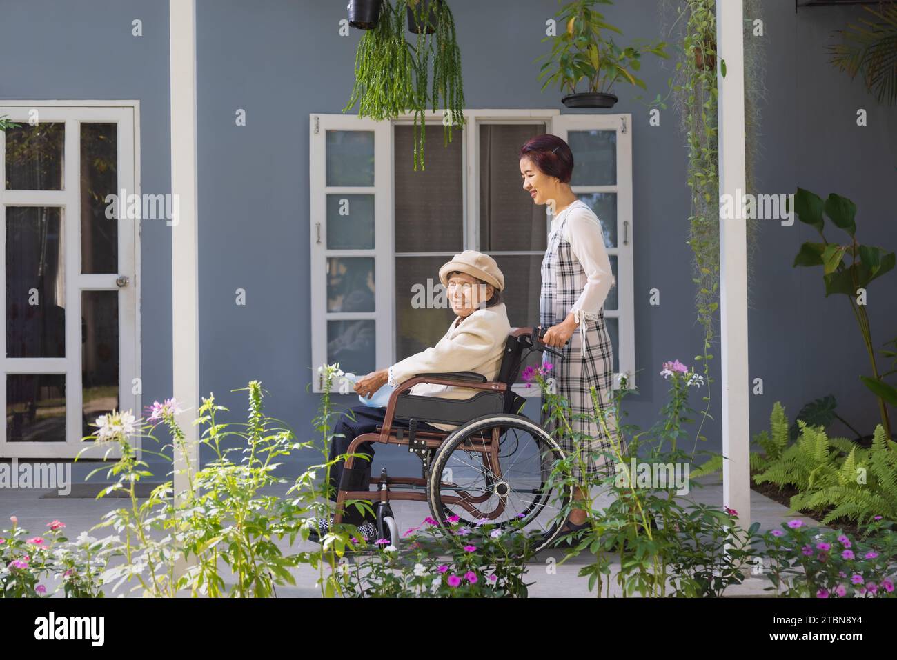 Elderly woman relax on wheelchair in backyard with daughter Stock Photo