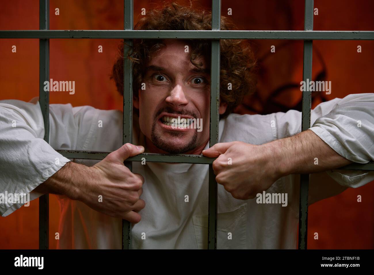 Crazy man prisoner and psychiatric hospital patient in cage Stock Photo