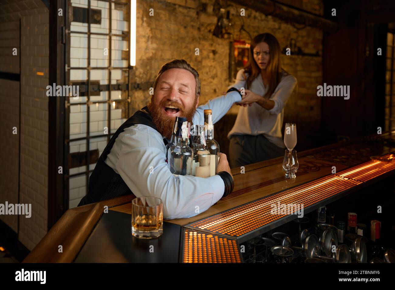 Wife trying to stop husband drinking to much alcohol Stock Photo