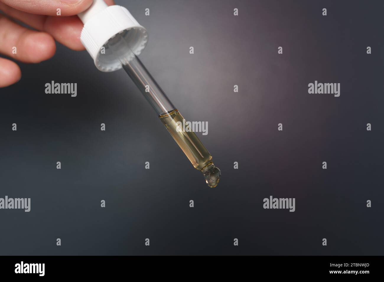 Hands holding a dropper filled with serum ready for application Stock Photo