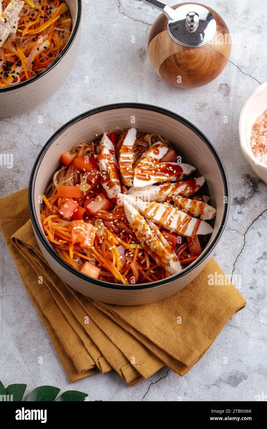 Asian rice noodles with vegetables, sauce and chicken in a bowl Stock Photo
