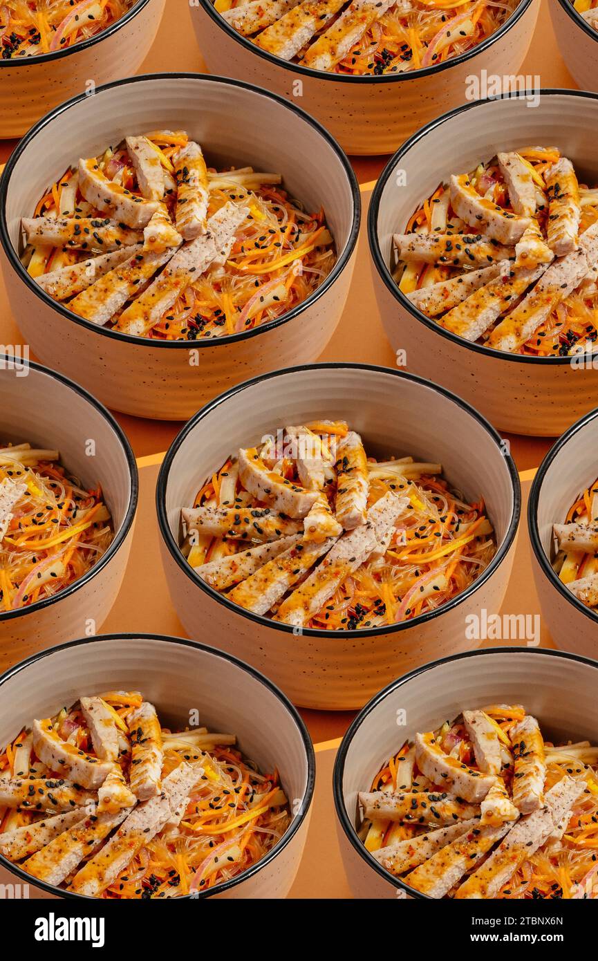 a pattern of bowls with Asian noodles on an orange background Stock Photo