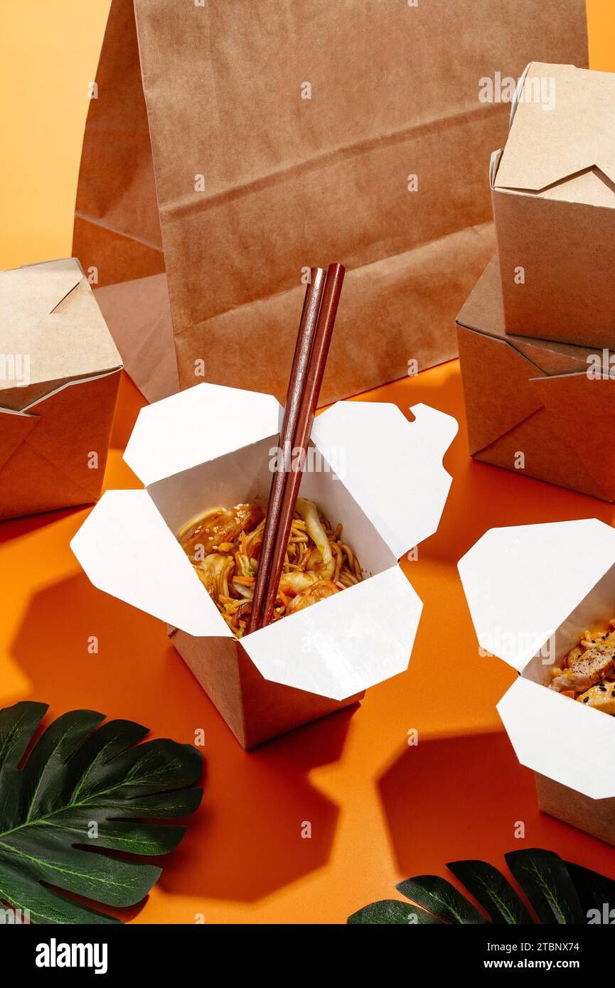 asian noodles with vegetables and chopsticks in takeaway paper box. Stock Photo