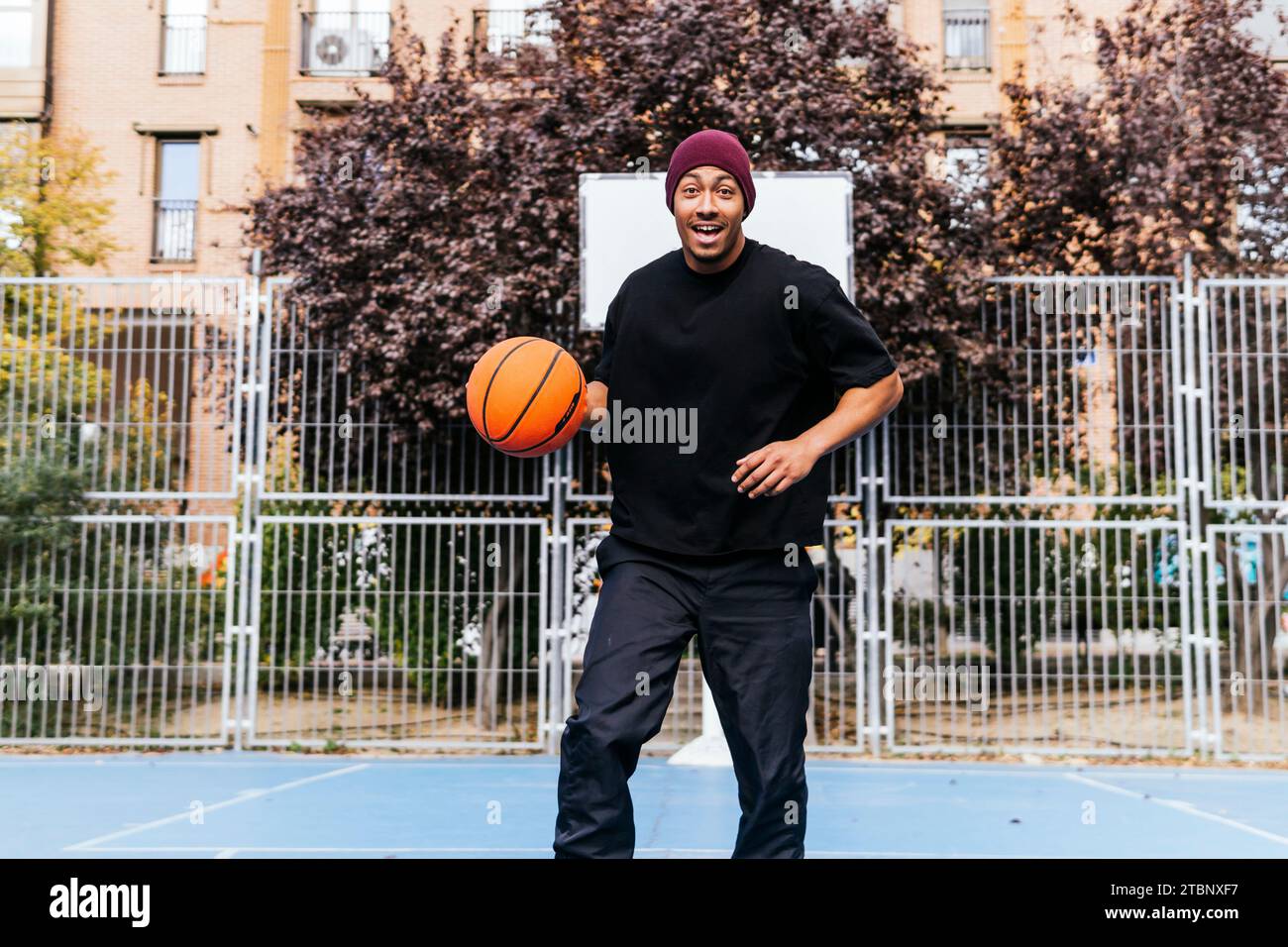 multiracial man playing with basketball on court Stock Photo