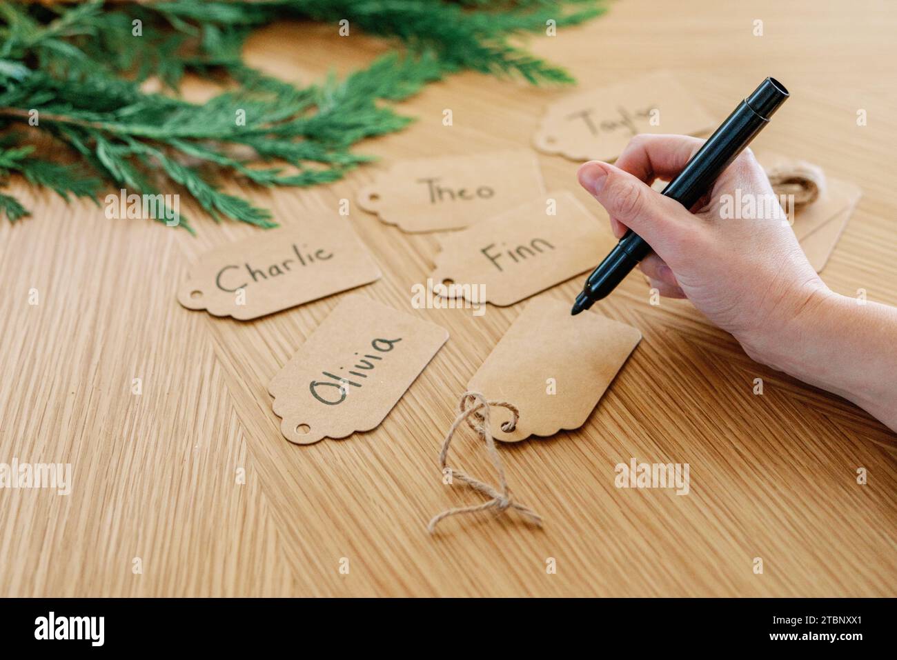 Handwriting names on holiday gift tags, one still blank Stock Photo