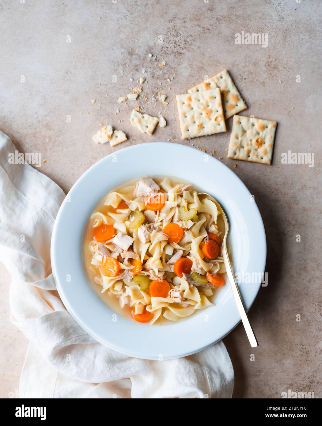 Top view chicken noodle soup in white bowl on beige background. Stock Photo