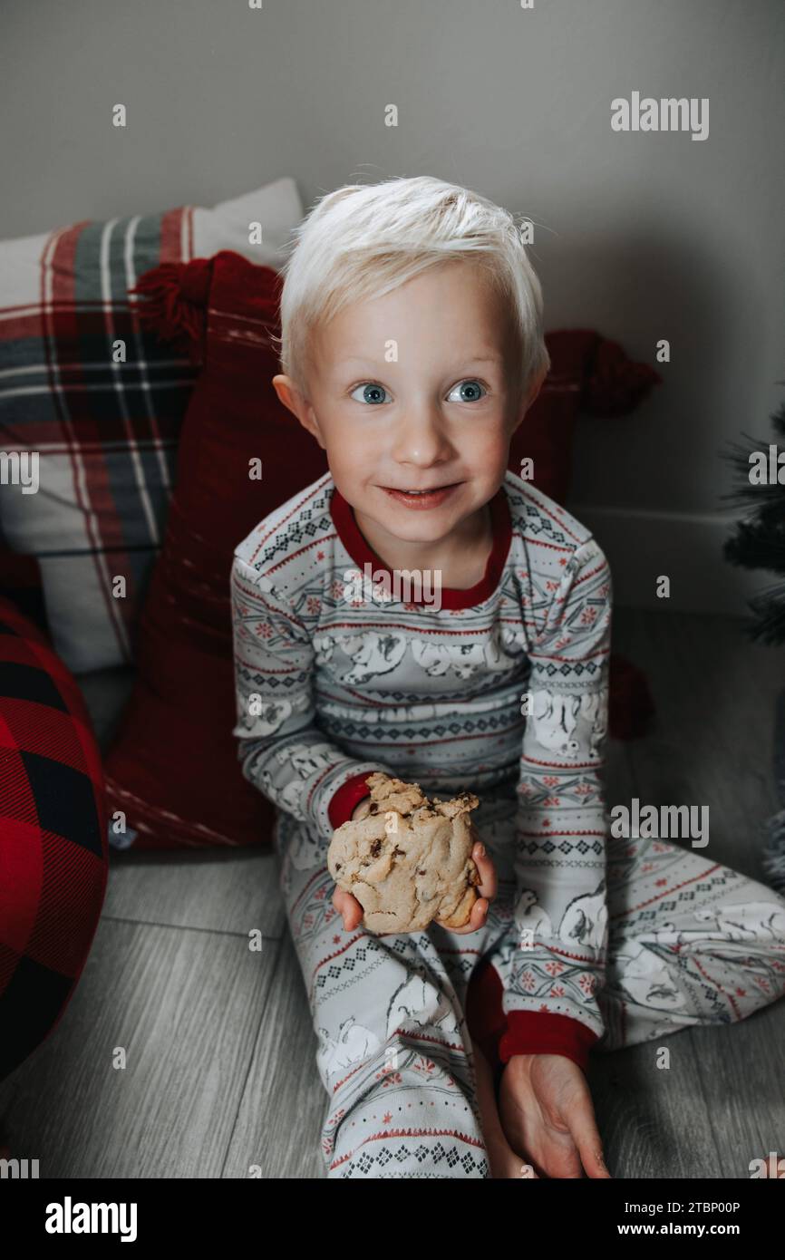 Boy happily eats cookie by tree Stock Photo